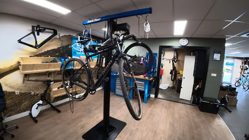 Een fiets in de montagestandaard in de werkplaats van Vision Sports