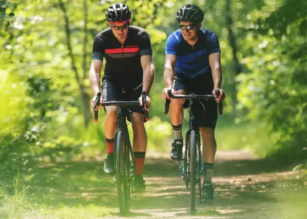 Twee renners op gravelfietsen op een bospad
