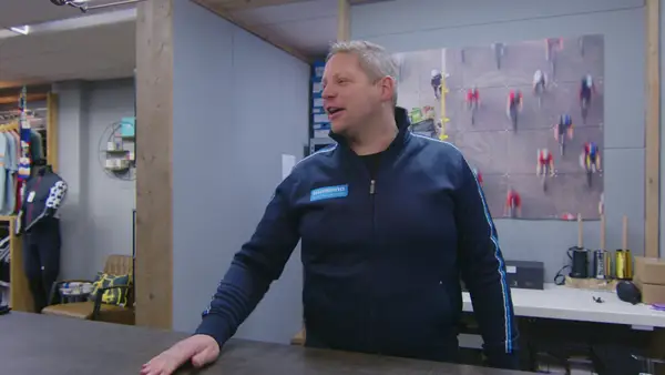 Remco achter de balie van Vision Sports met een racefiets ernaast
