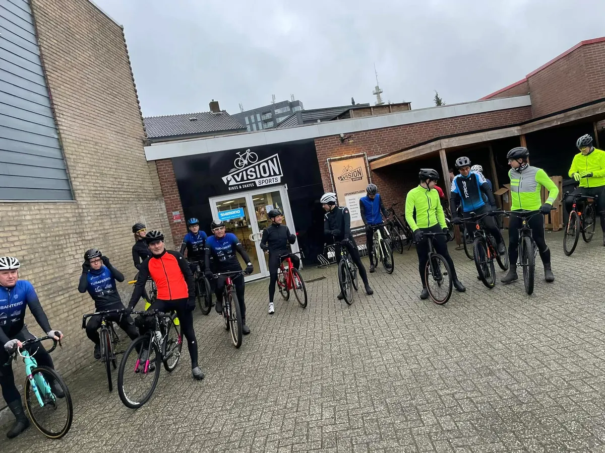 Wielrenners verzamelen voor de winkel van Vision Sports in Hengelo