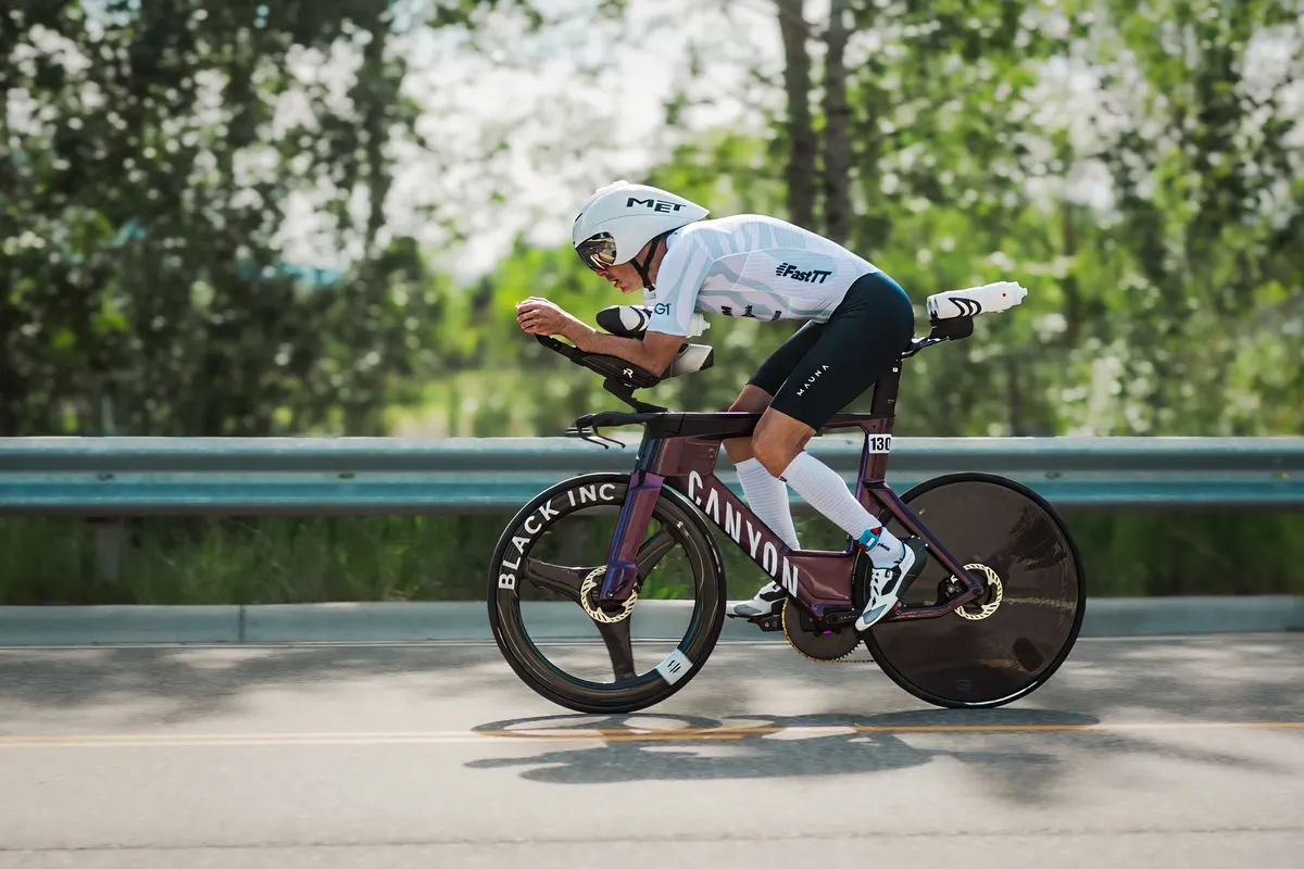 Renner in aerohouding op een tijdritfiets met schijfwiel
